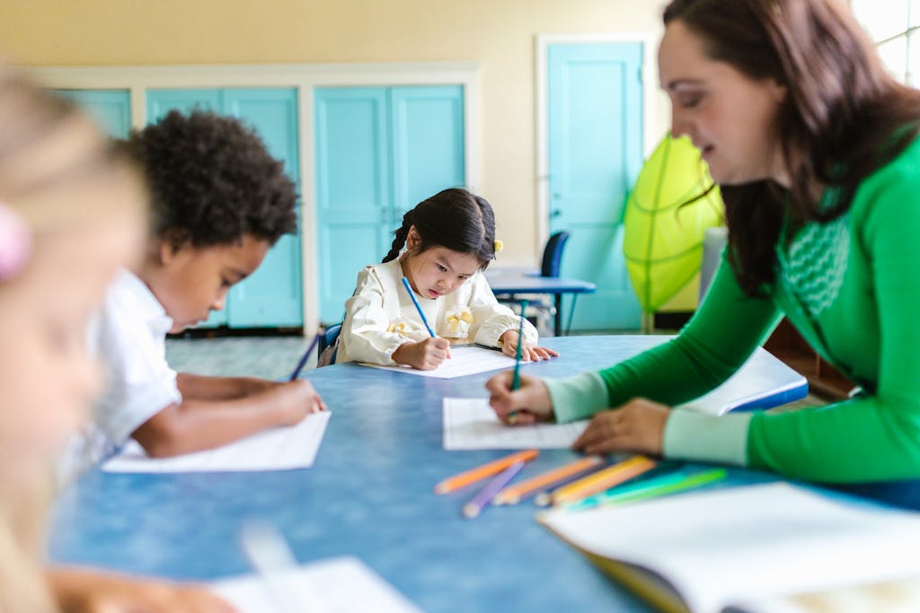 Kids focused on drawing and learning with a teacher's guidance in a bright classroom.