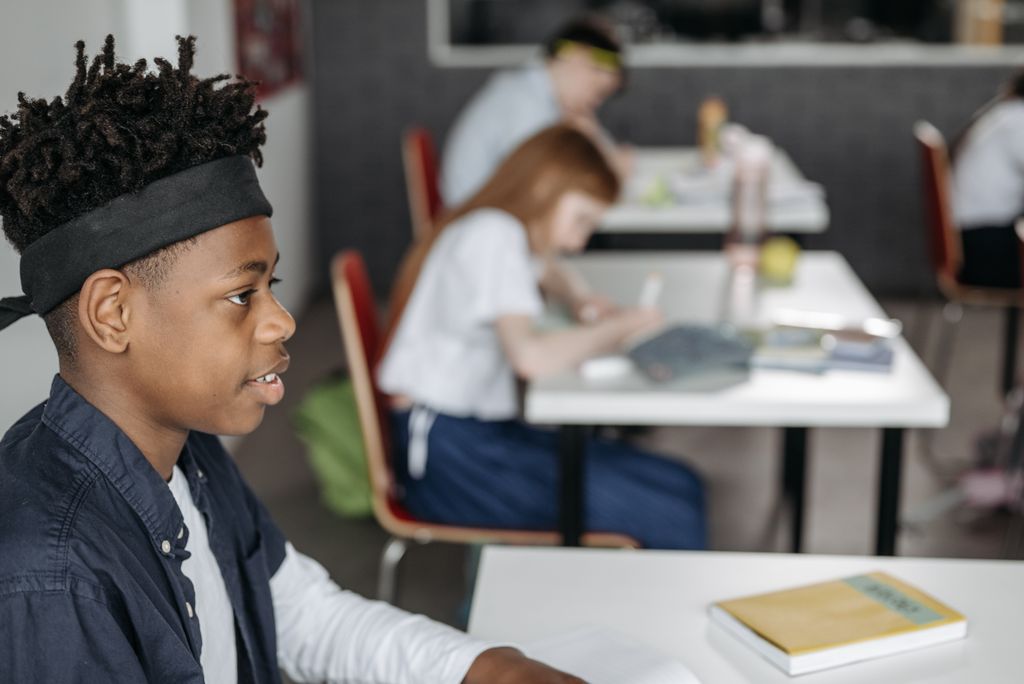 Black child sitting attentively in a classroom setting, focusing on learning.